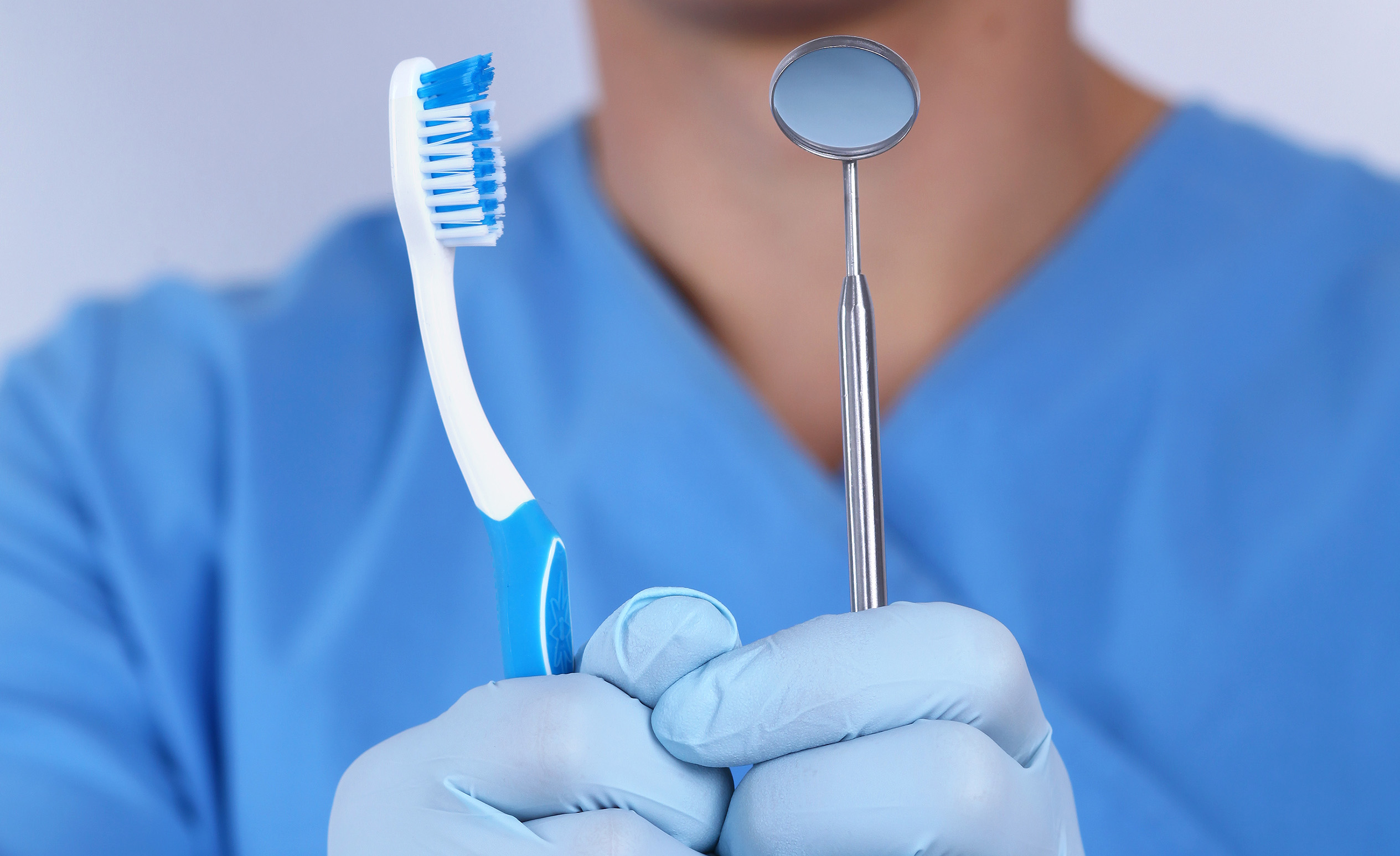 Budapesti fogorvos, Dr. Varajti Artúr fog egy fogkefét és egy fogászati fogtükört.