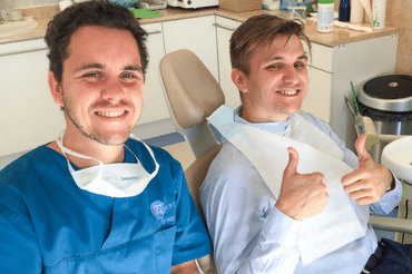 Bölcsességfog eltávolítás után Dr. Varajti Artúr és páciense mosolyog a budapesti fogászati és szájsebészeti rendelőben.